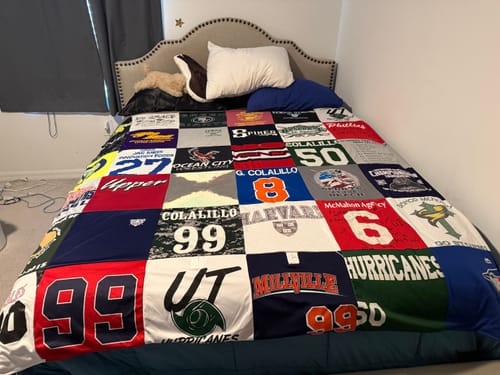 Customer's custom T-Shirt Quilt made from colorful sports jerseys and school shirts, spread across a bed.