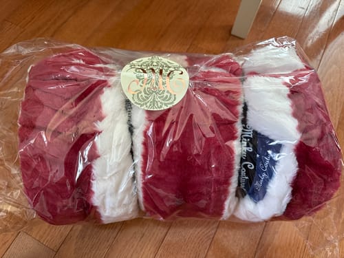Customer's new Hugs Flag Blanket, showing its plush red and white stripes while folded in packaging.