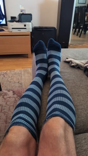 En recensent som sitter i en soffa och bär de blårandiga Diasocks Stödstrumporna.