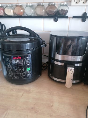 Customer's black Multicooker Novio SteelCook with its digital display on, sitting on a kitchen counter next to another appliance.