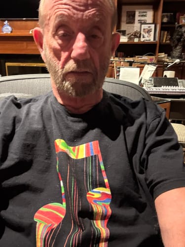 Reviewer wearing the black Dead String Society T-Shirt with a colorful, dripping musical note graphic.