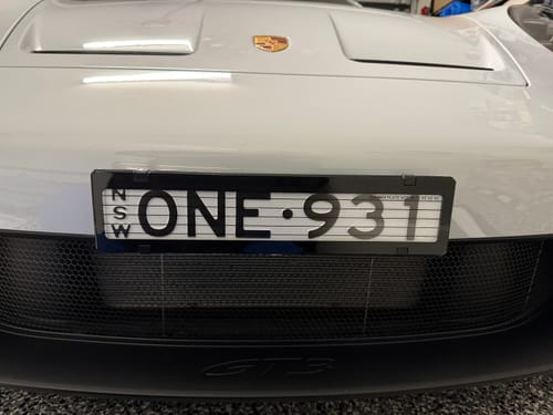Reviewer's black Miniature Plinth mounted cleanly on the front bumper of a white Porsche 911 GT3.