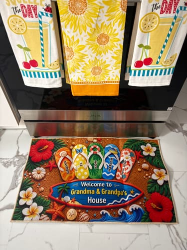 Reviewer's 'Welcome to Grandma & Grandpa's House' doormat on a floor, personalized with names on colorful flip-flops.