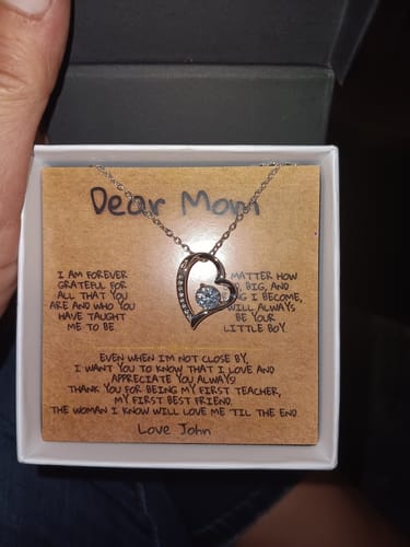 Customer holds the open Dear Mom Necklace Gift Set, showing the heart necklace on its personalized message card.