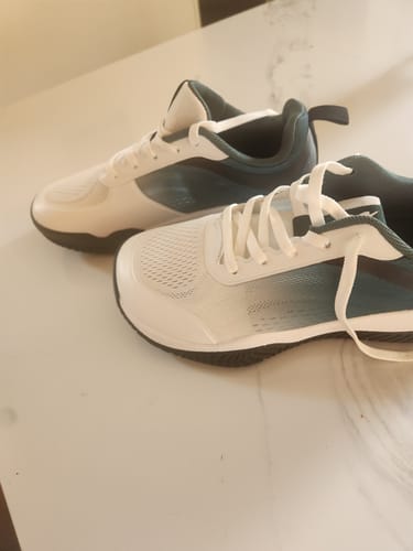 Customer's white and dark green CUURT Muuv court shoes resting on a white marble-patterned surface.