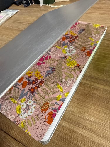 Customer's Kristy Planner with its silver cover partially lifted, showing the floral Starlight design underneath.