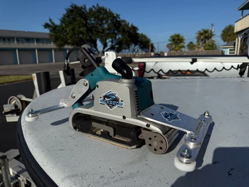 Reviewer's Zirconia Sanding Belt installed on a modified belt sander for a racing program, resting on a boat.