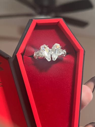 Close-up of a customer's PROMISE RING with two clear, coffin-shaped stones inside a red coffin-shaped box.
