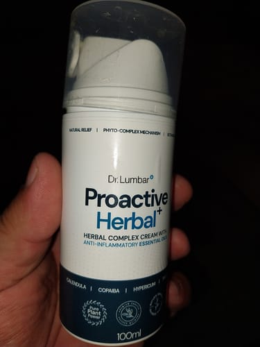 Customer holding the white pump bottle of Proactive Herbal+ Cream in a dark room.