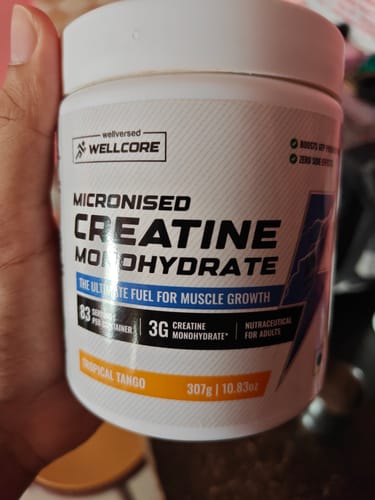 Customer holding a white tub of Wellcore Micronised Creatine Monohydrate in Tropical Tango flavor.