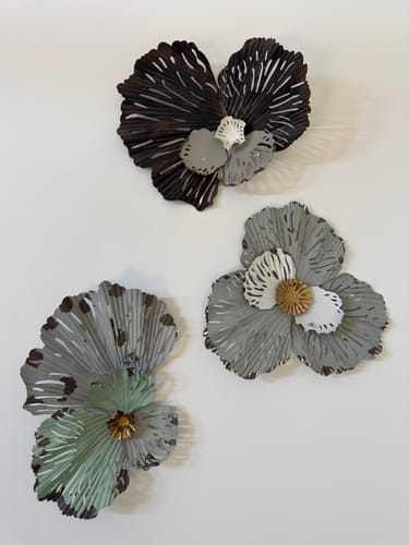 Customer's three Flower Metal Wall Art pieces in grey, black, and green, displayed together on a white wall.