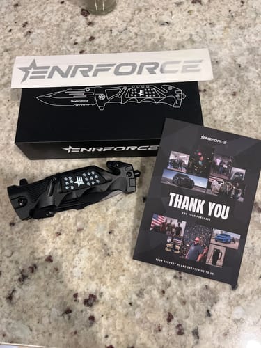 Customer's black Tactical Folding Knife displayed with its packaging and a thank you card on a counter.