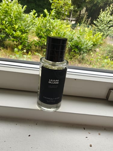 Customer's bottle of Lilium Blume Eau de Parfum on a windowsill with a green, leafy background.