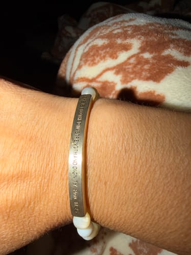 A customer's wrist wearing the inspirational beaded bracelet with its engraved silver-tone bar.