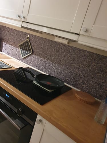 Kundens Clemont terrazzo selvklebende fliser installert som en kjøkkenvegg bak en koketopp.