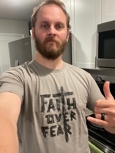 Customer wearing the grey Faith Over Fear Tee, showing the distressed front graphic in a kitchen.