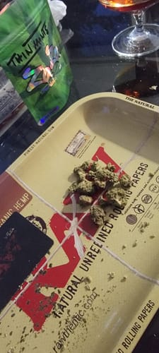 Customer's small Thin Mintz Littles buds on a rolling tray, with the green product pouch visible in the background.