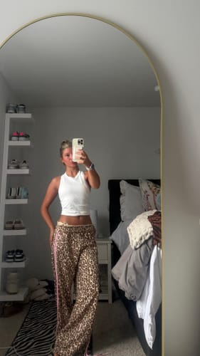 Reviewer in a bedroom mirror selfie wearing the leopard print Bow Detail Track Pants with a pink side stripe.
