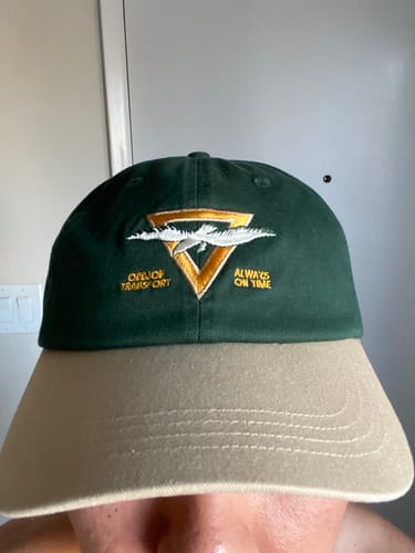 A reviewer wears the Big Dad Hat Two Tone, showing a close-up of the green crown and tan brim.