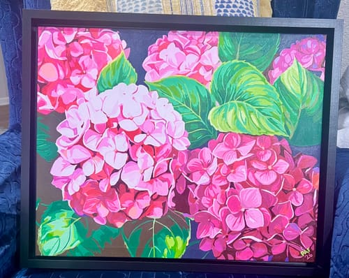 Customer's completed Pink Hydrangea paint by numbers artwork, displayed in a black frame on a blue chair.