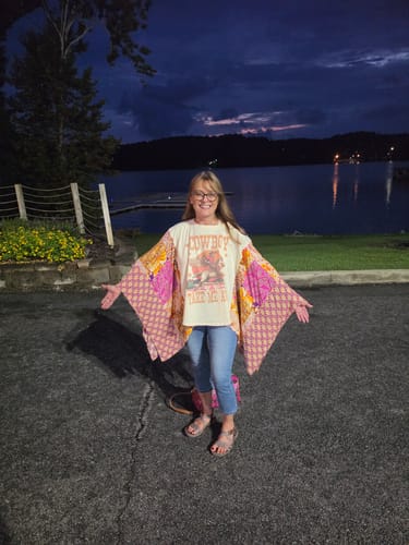 Reviewer holding her arms out to display the large, patterned sleeves of the Cowboy Take Me Away Poncho Top.