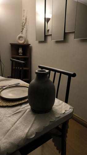 Cliente muestra su Florero Madera oscuro sobre una silla en un comedor.