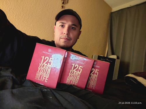 Cliente mostrando tres cajas rojas del perfume Swiss Army 125 YEARS en su regazo.