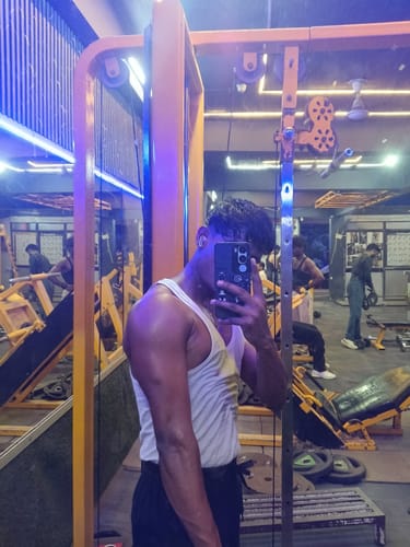 Reviewer in a gym taking a mirror selfie showing their muscular arm, attributing results to Wellcore Creatine Monohydrate.
