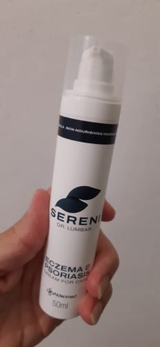 Customer's hand holding the white bottle of SERENI Eczema & Psoriasis cream.