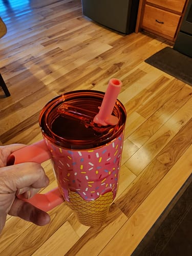 Customer's hand holding a Mystery Thicc Buddy tumbler with a pink ice cream cone design and handle.