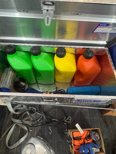 Reviewer's green, yellow, and orange 2.5 Gallon Jugs lined up inside a truck's metal toolbox.