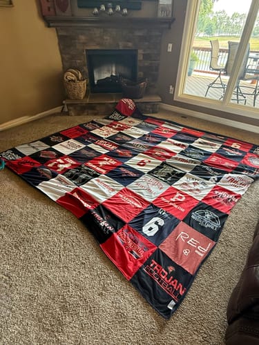 Customer's large Premium T Shirt Quilt with red and black shirts laid out on a living room floor.