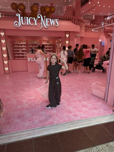 Customer's child posing at the entrance of a pink store for their Walk Ins experience.