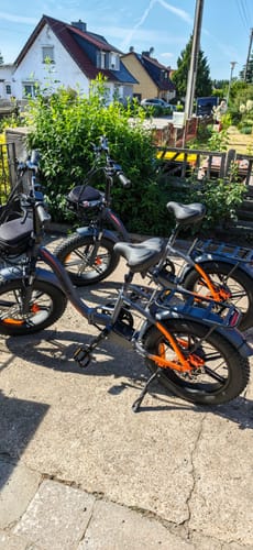 Customer's two black Vakole Y20 Pro foldable fat bikes parked on a sunny paved driveway outdoors.