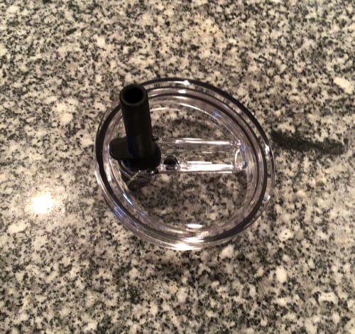 Customer's clear Thicc Buddy replacement flip straw lid resting on a speckled countertop.