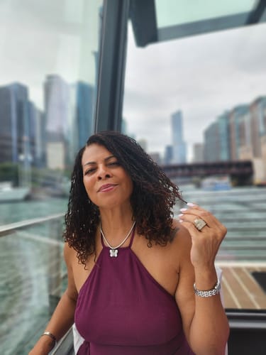 Smiling woman with curly hair by a window, customer photo