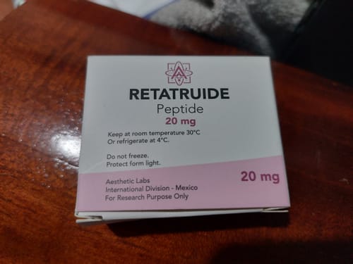 Un cliente muestra la caja de 'Retatruide Peptide 20 mg' de Aesthetic Labs sobre una mesa de madera.