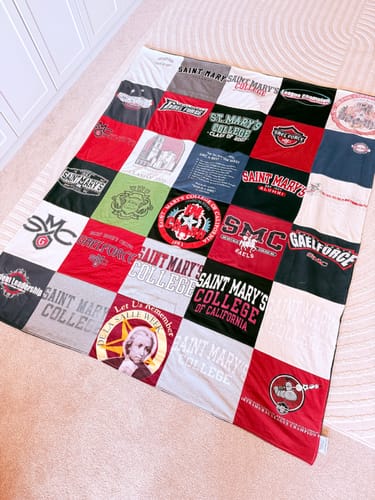 Customer's Project Repat T-Shirt Quilt laid flat, featuring a colorful grid of various college-themed t-shirt logos.