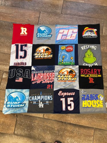 Customer's Project Repat T-Shirt Quilt laid on the floor, showing a patchwork of colorful t-shirts with various logos.