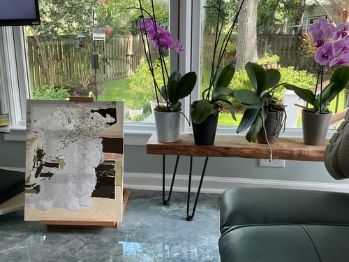 Customer's Custom Paint by Numbers Kit canvas on an easel near a window with orchids on a wooden bench.