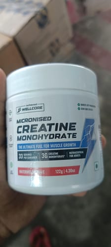 Customer's hand holding a jar of Wellcore Pure Micronised Creatine Monohydrate Watermelon Wave supplement.