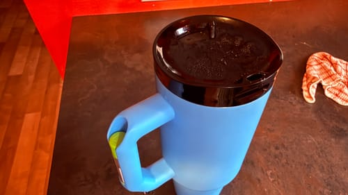 Customer's blue Thicc Buddy 40oz with a black lid resting on a dark countertop.
