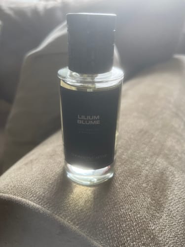 Customer's Lilium Blume Eau de Parfum bottle with a black label, resting on a textured surface.