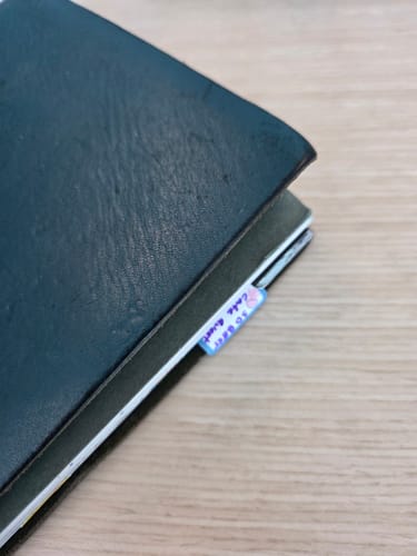 Customer's Monthly Tabs Dreamy Jellies palette sticker applied as a page tab on the edge of a dark notebook.