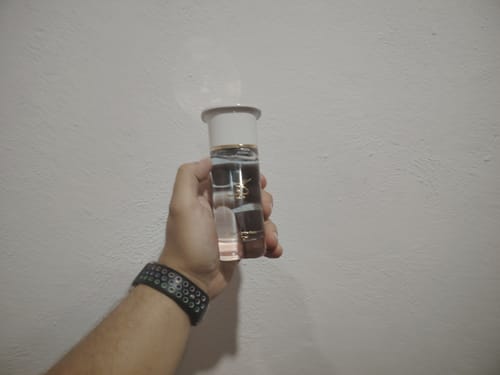 Mano sosteniendo el frasco de perfume Ahmed al Maghribi KAAF de vidrio transparente con tapa blanca.