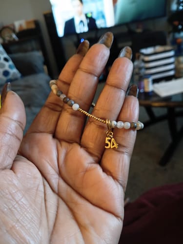 Reviewer's POSITIVE MIND - POSITIVE VIBES - POSITIVE LIFE bracelet with gold-toned charm on wrist, close-up.
