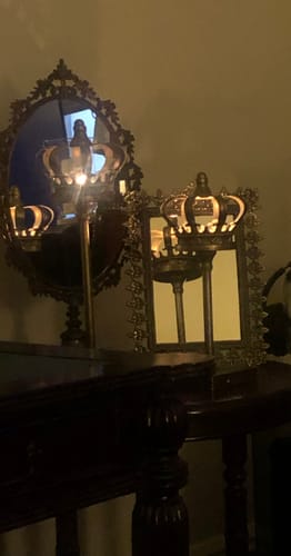 Customer's Jade Crown tealight holders in antique gold, lit and placed in front of mirrors on a table.