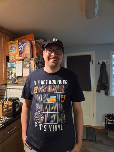 Customer's Record Collector T-shirt on a smiling person in a kitchen.