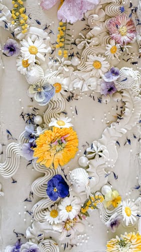 Reviewer's White Daisies freeze dried flowers used as delicate decorative accents on a frosted cake.