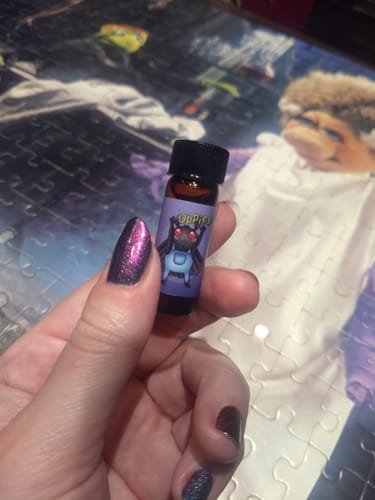 Customer's hand holding the Just A Lil' Moth Guy Oil Dram with a cute moth illustration on the label.